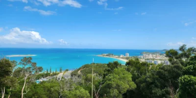 从林木覆盖的山丘俯瞰碧蓝海湾与努美阿市区